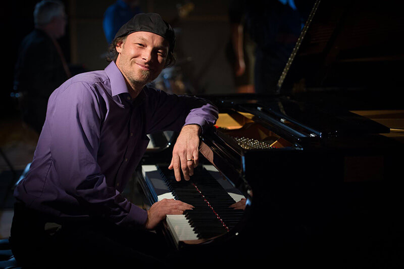 Ira Friedman leaning on a piano