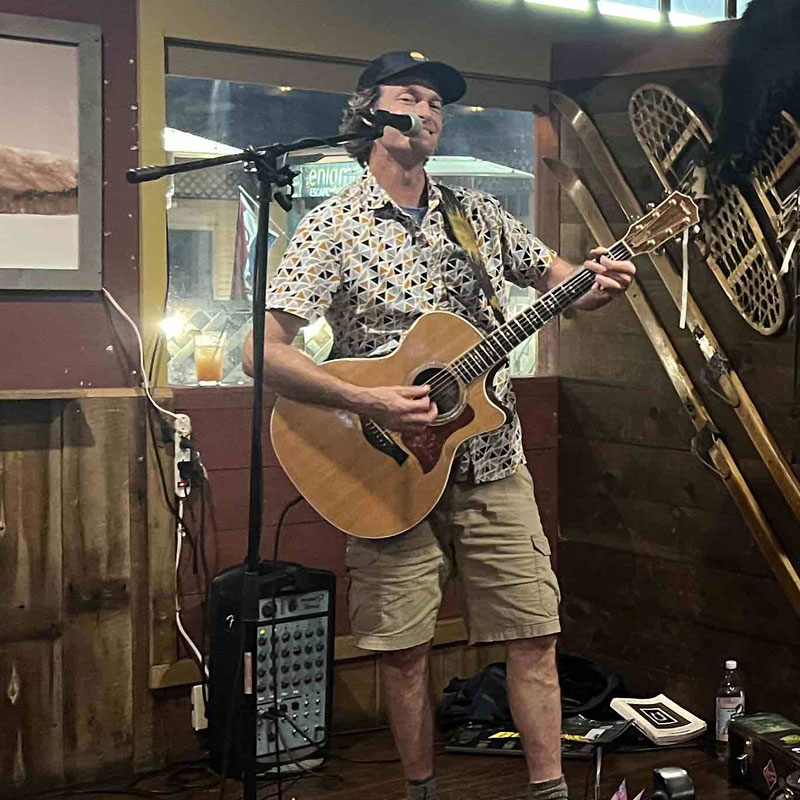 Doug Wells playing acoustic guitar on stage